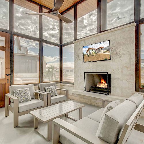 The image depicts a cozy sunroom with a fireplace, comfortable seating, a mounted TV, and large windows offering an outdoor view, ending the sentence.