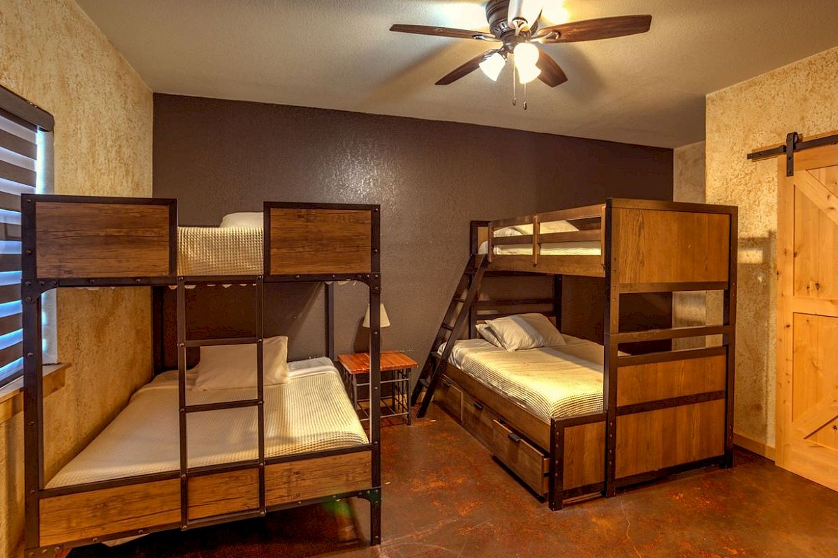 The image shows a room with two sets of wooden bunk beds, a ceiling fan, and a sliding barn door.