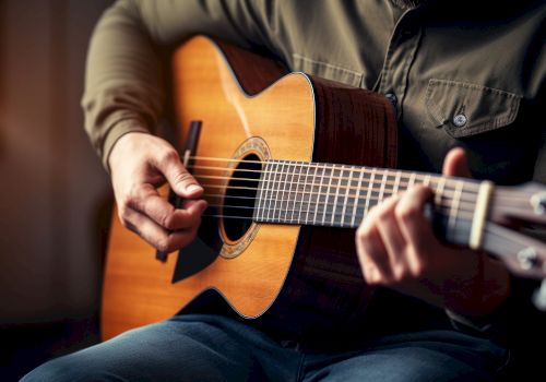 A person playing an acoustic guitar, focusing on their hands and the instrument, with a warm, blurred background.
